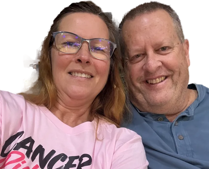 Hallie Hastings and her husband Robert, heads together, smiling at the camera. Hallie is wearing the fundraiser's pink t-shirt, printed "Cancer Picked The Wrong Girl" above a pink ribbon and #Rally4Hallie.